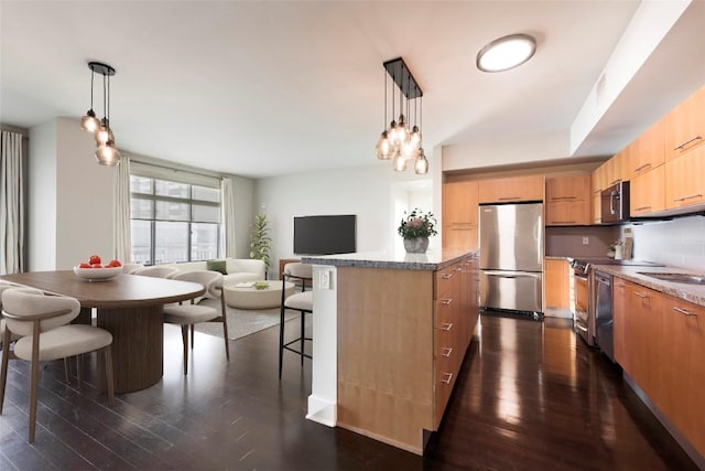 kitchen with stainless steel appliances, a kitchen island, dark hardwood / wood-style floors, and pendant lighting