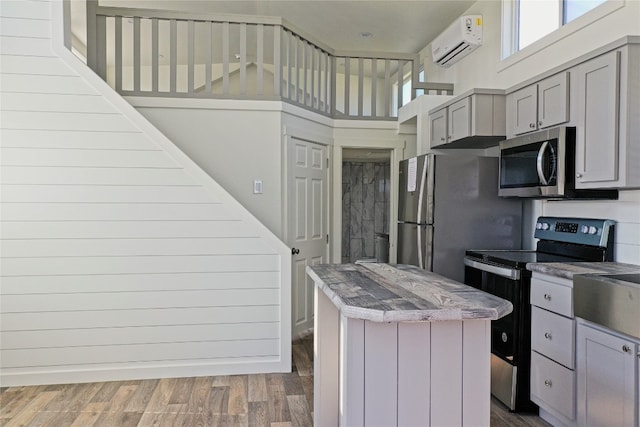 kitchen featuring a wall mounted AC, dark wood-type flooring, gray cabinets, appliances with stainless steel finishes, and a high ceiling