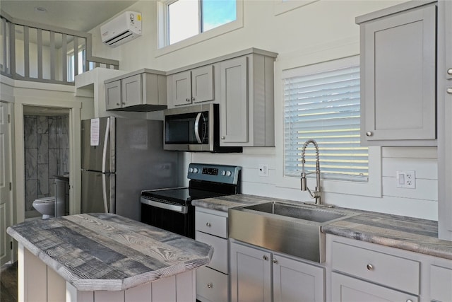 kitchen featuring gray cabinetry, stainless steel appliances, sink, and an AC wall unit