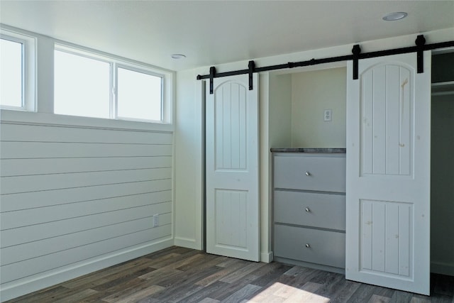 interior space featuring a barn door, dark wood-type flooring, and multiple windows