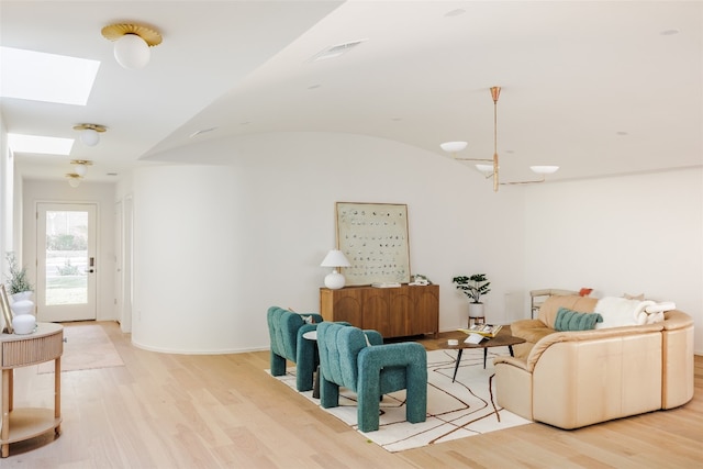 living room with vaulted ceiling with skylight and light hardwood / wood-style floors