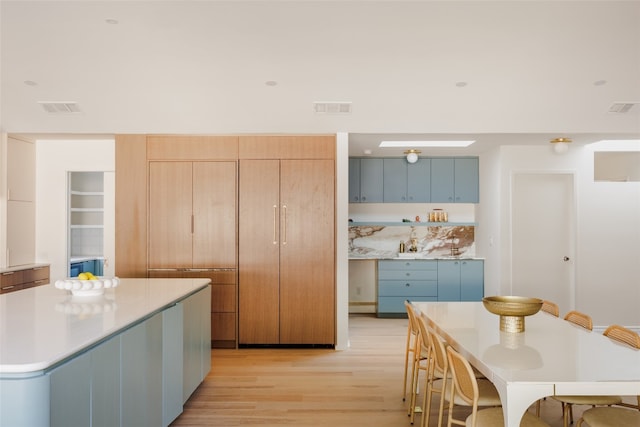 kitchen with blue cabinets, light hardwood / wood-style floors, and a center island