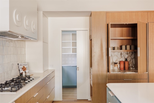 kitchen with stainless steel gas stovetop, light hardwood / wood-style flooring, backsplash, and extractor fan