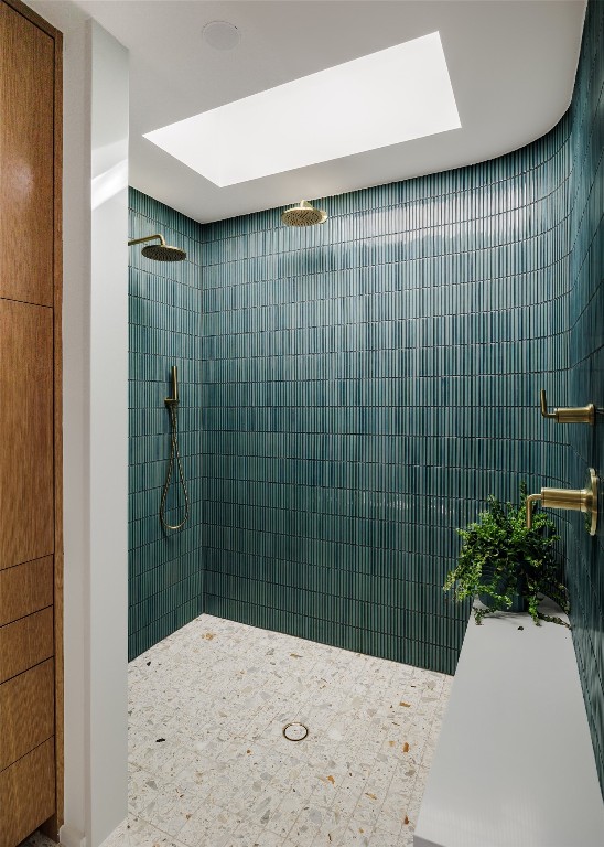 bathroom featuring a tile shower and a skylight