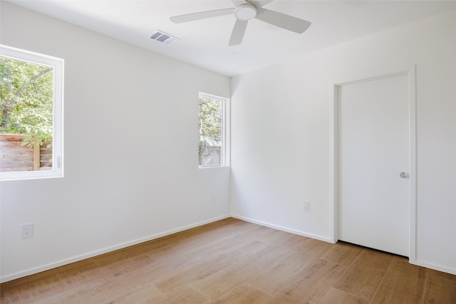 spare room featuring ceiling fan, light hardwood / wood-style flooring, and a wealth of natural light