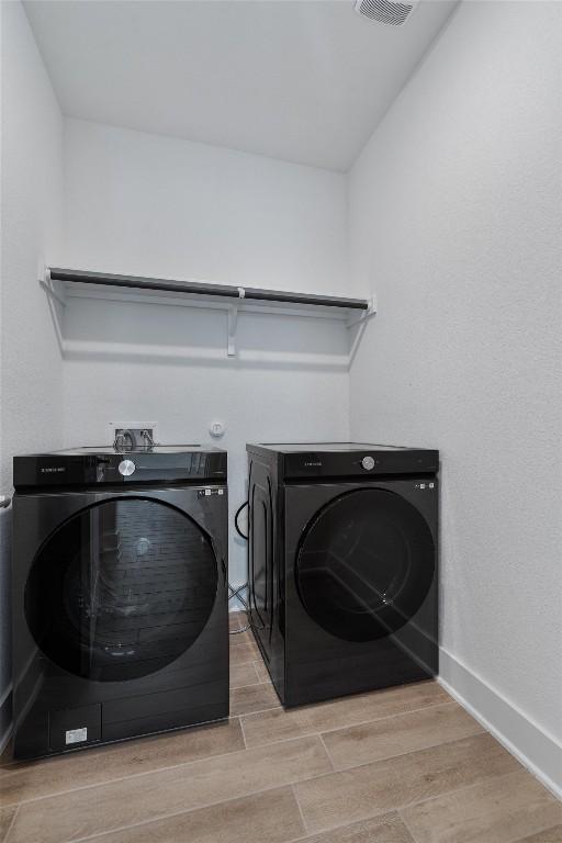 1029 Villa Rialto Vw, Leander, TX 78641 - clothes washing area featuring wood finished floors, separate washer and dryer, and baseboards