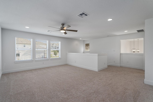 unfurnished room with ceiling fan with notable chandelier and light carpet