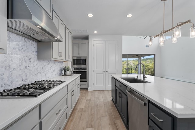 kitchen featuring pendant lighting, sink, appliances with stainless steel finishes, tasteful backsplash, and light stone counters