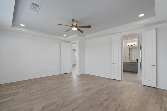 1029 Villa Rialto Vw, Leander, TX 78641 - unfurnished bedroom featuring a tray ceiling, light wood finished floors, baseboards, recessed lighting, and ensuite bathroom