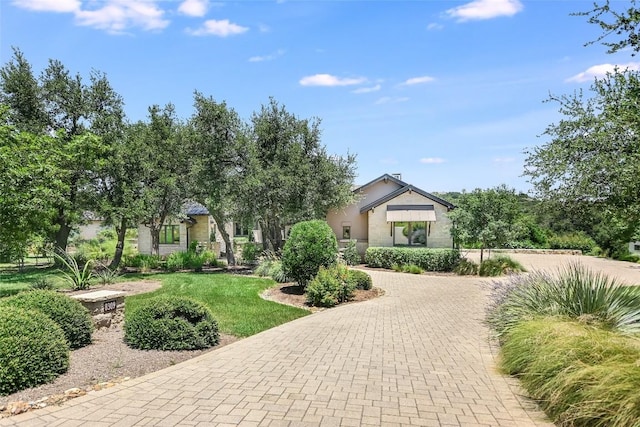 view of front of property with decorative driveway, a front yard, and stucco siding