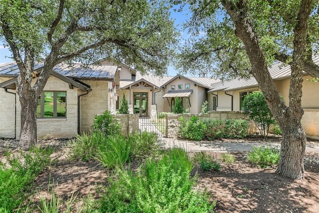 8309 Verde Mesa Cv, Austin, TX 78738 - view of front of home with a fenced front yard, stone siding, a standing seam roof, metal roof, and french doors