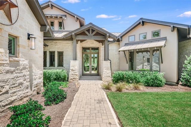 view of exterior entry with stone siding, metal roof, a standing seam roof, french doors, and stucco siding