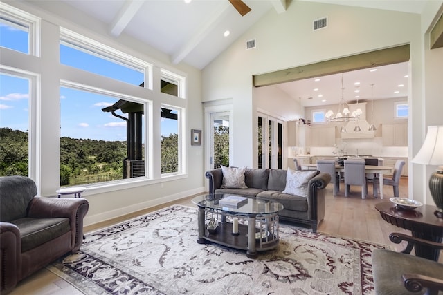 living room with high vaulted ceiling, beam ceiling, light hardwood / wood-style floors, and ceiling fan with notable chandelier