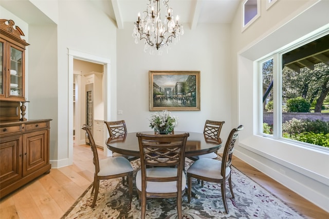 dining space with a notable chandelier, light wood-type flooring, and lofted ceiling with beams