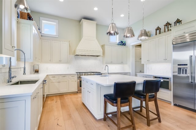 kitchen featuring light wood-type flooring, sink, custom range hood, a center island, and high quality appliances