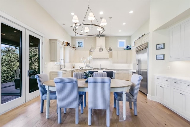 dining area featuring a chandelier, recessed lighting, vaulted ceiling, french doors, and light wood finished floors