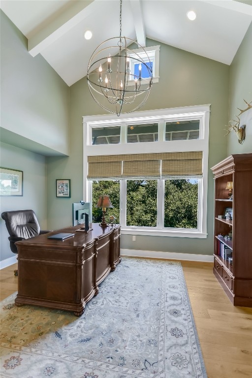 office space featuring a notable chandelier, a wealth of natural light, beam ceiling, and light wood-type flooring