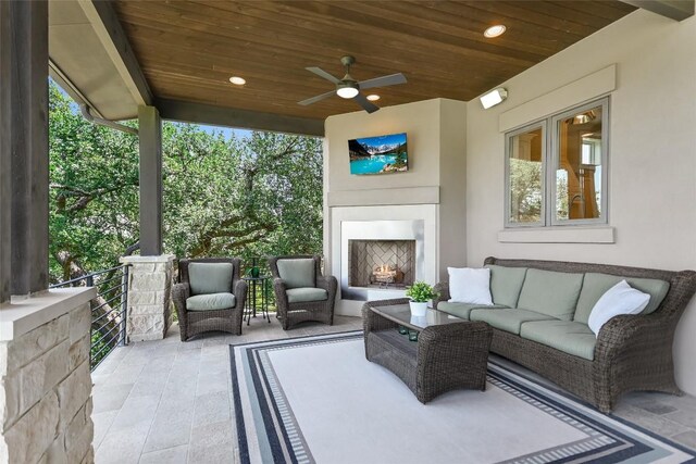 view of patio / terrace featuring ceiling fan and an outdoor living space with a fireplace