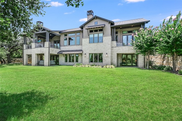 back of property featuring a balcony, a standing seam roof, metal roof, and a yard