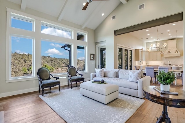 living room with baseboards, visible vents, beamed ceiling, light wood-style floors, and high vaulted ceiling