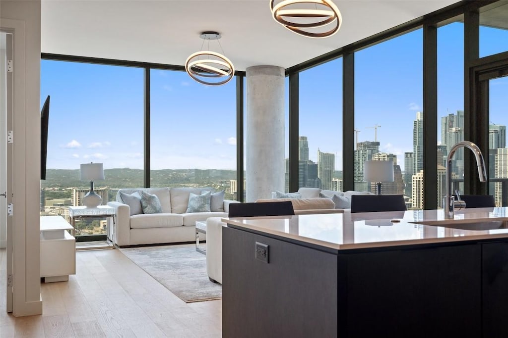 kitchen with a view of city, light countertops, expansive windows, a sink, and light wood-type flooring