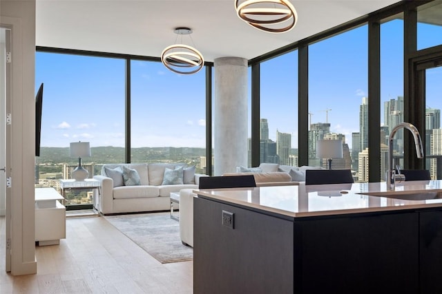 kitchen with a view of city, light countertops, expansive windows, a sink, and light wood-type flooring