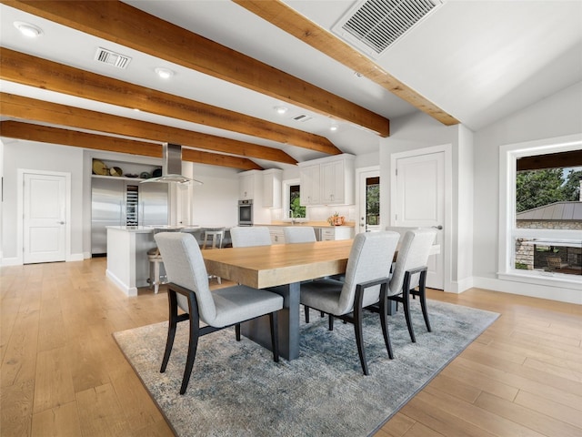 dining area with lofted ceiling with beams and light hardwood / wood-style flooring