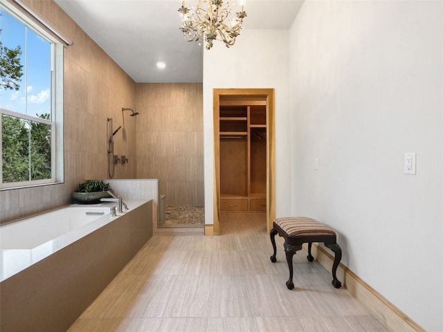 bathroom featuring a healthy amount of sunlight, independent shower and bath, and a notable chandelier