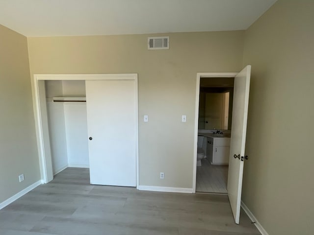 unfurnished bedroom with a closet, sink, and light hardwood / wood-style flooring