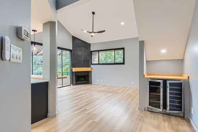 1707 Spyglass Dr Unit 60, Austin, TX 78746 - unfurnished living room with wine cooler, light wood finished floors, high vaulted ceiling, a fireplace, and a dry bar