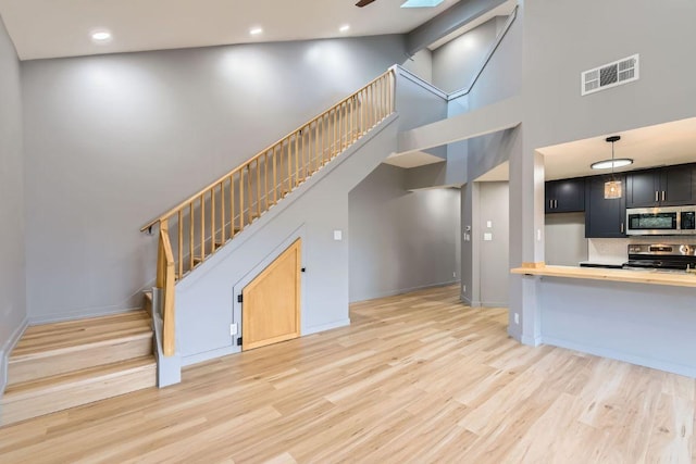 1707 Spyglass Dr Unit 60, Austin, TX 78746 - unfurnished living room with a towering ceiling, stairs, light wood finished floors, recessed lighting, and a ceiling fan