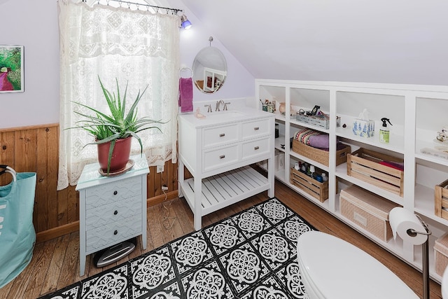 bedroom featuring wooden walls, vaulted ceiling, dark hardwood / wood-style flooring, and sink