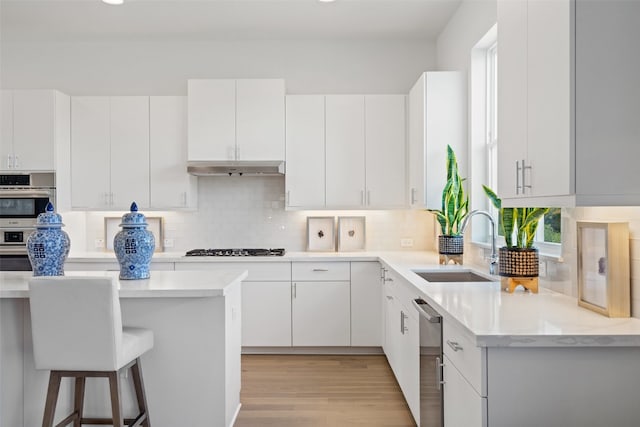 kitchen featuring a kitchen breakfast bar, white cabinets, light hardwood / wood-style floors, and sink