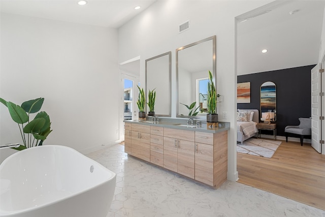 bathroom featuring vanity, a tub to relax in, a towering ceiling, and hardwood / wood-style floors