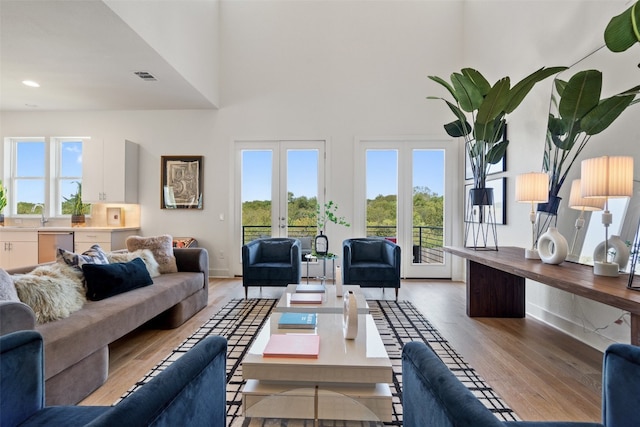 living room with light wood-type flooring, sink, french doors, and plenty of natural light