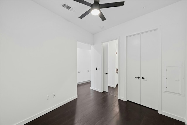 unfurnished bedroom featuring dark hardwood / wood-style flooring, ceiling fan, and a closet