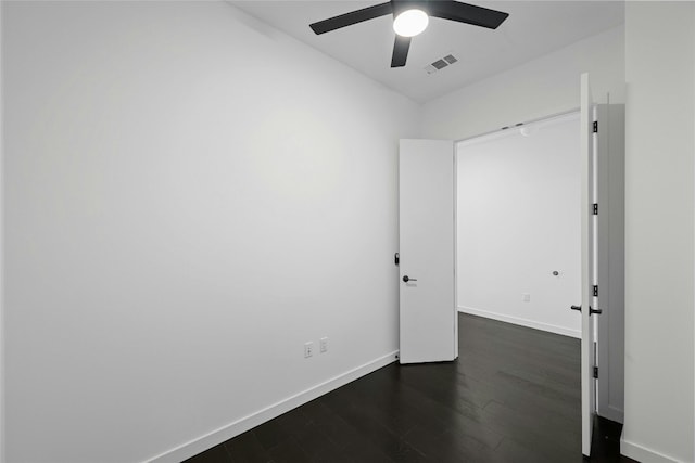 empty room featuring dark wood-type flooring and ceiling fan