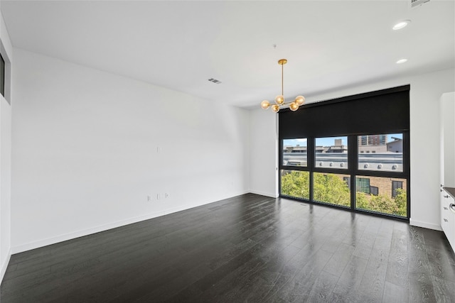 spare room with dark wood-type flooring and a chandelier