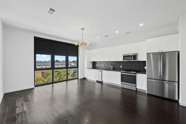 kitchen featuring appliances with stainless steel finishes, white cabinets, dark hardwood / wood-style floors, sink, and a notable chandelier