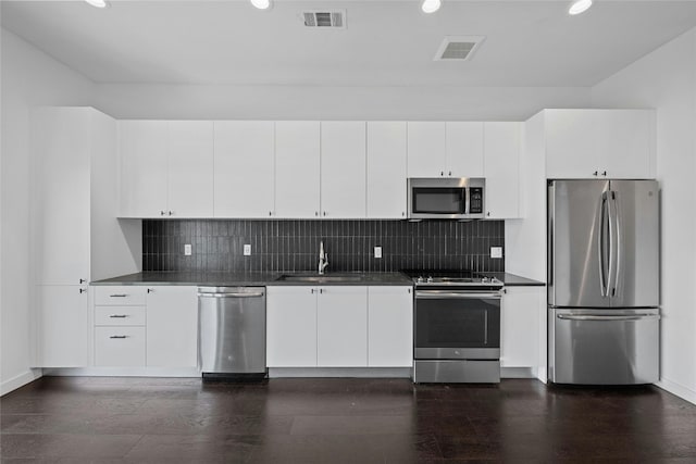 kitchen with white cabinets, stainless steel appliances, sink, and dark hardwood / wood-style flooring