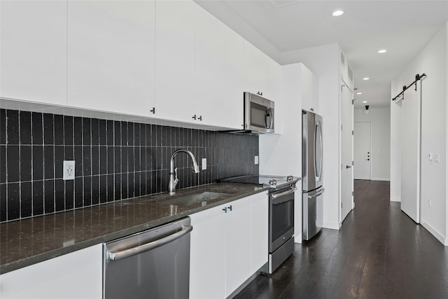 kitchen featuring sink, white cabinetry, a barn door, stainless steel appliances, and dark hardwood / wood-style flooring