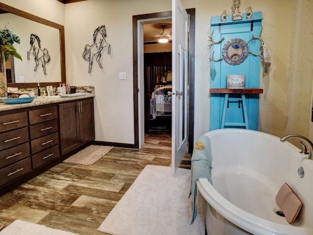 bathroom featuring a tub to relax in, ceiling fan, hardwood / wood-style flooring, and vanity