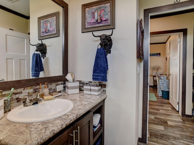 bathroom featuring ornamental molding, vanity, decorative backsplash, and hardwood / wood-style flooring