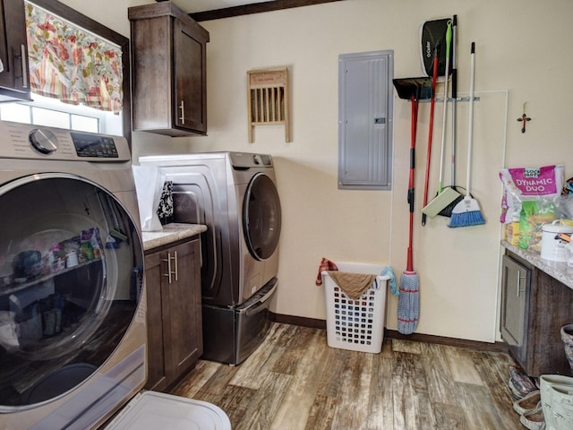 washroom featuring washing machine and dryer, electric panel, cabinets, ornamental molding, and hardwood / wood-style floors