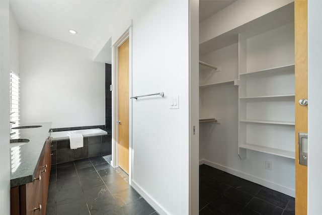 bathroom with tiled tub and vanity