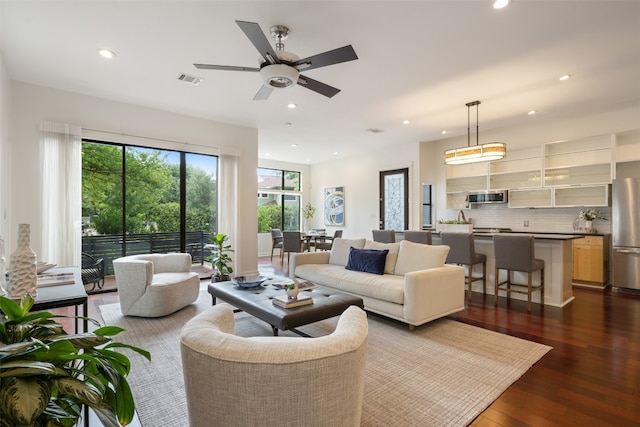 living room featuring ceiling fan and dark hardwood / wood-style flooring