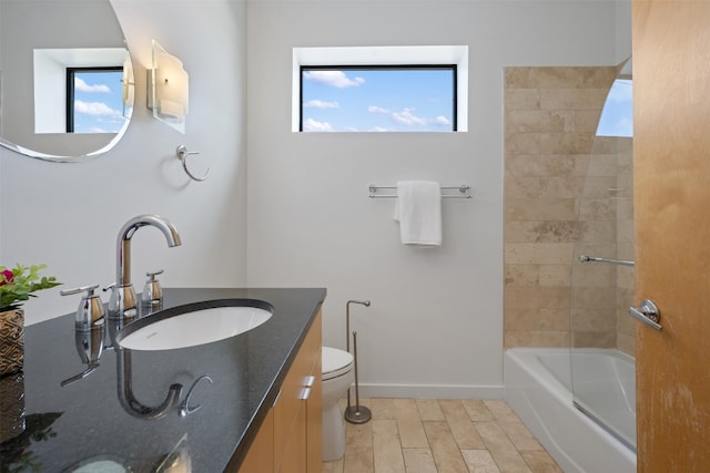 full bathroom featuring vanity, tiled shower / bath, wood-type flooring, and toilet