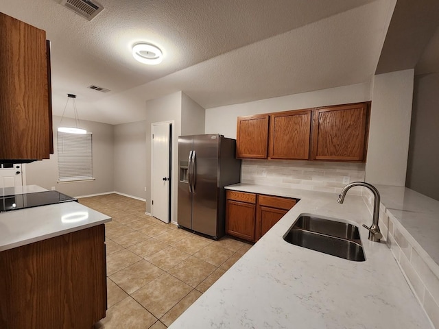 kitchen with stainless steel fridge, light tile patterned flooring, hanging light fixtures, a textured ceiling, and sink