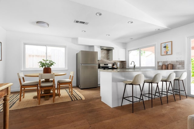 kitchen with white cabinets, appliances with stainless steel finishes, dark hardwood / wood-style floors, and kitchen peninsula