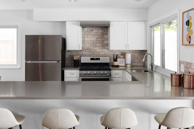 kitchen with white cabinetry, tasteful backsplash, a breakfast bar area, stainless steel appliances, and sink